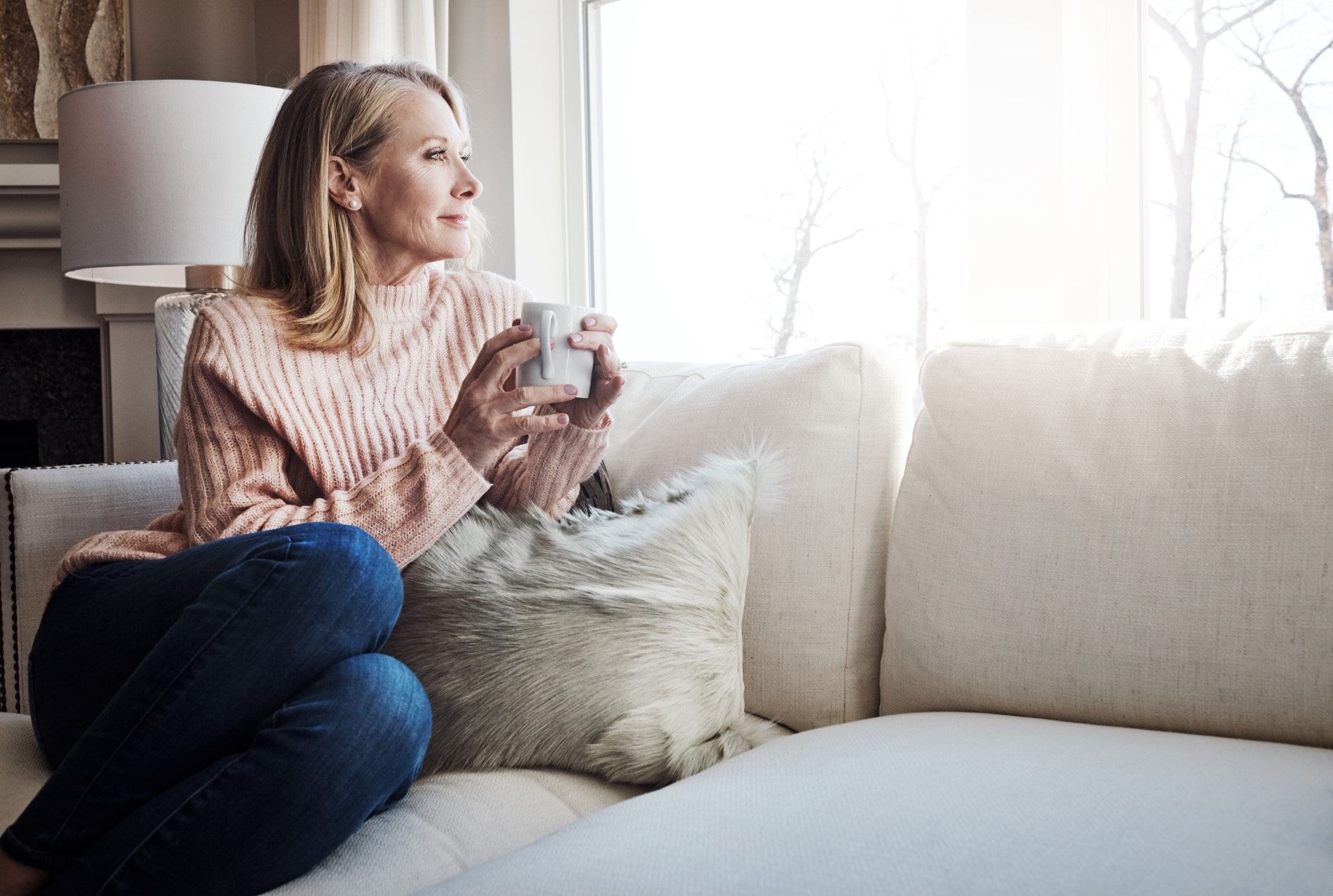 Woman holding a mug, looking outside the window